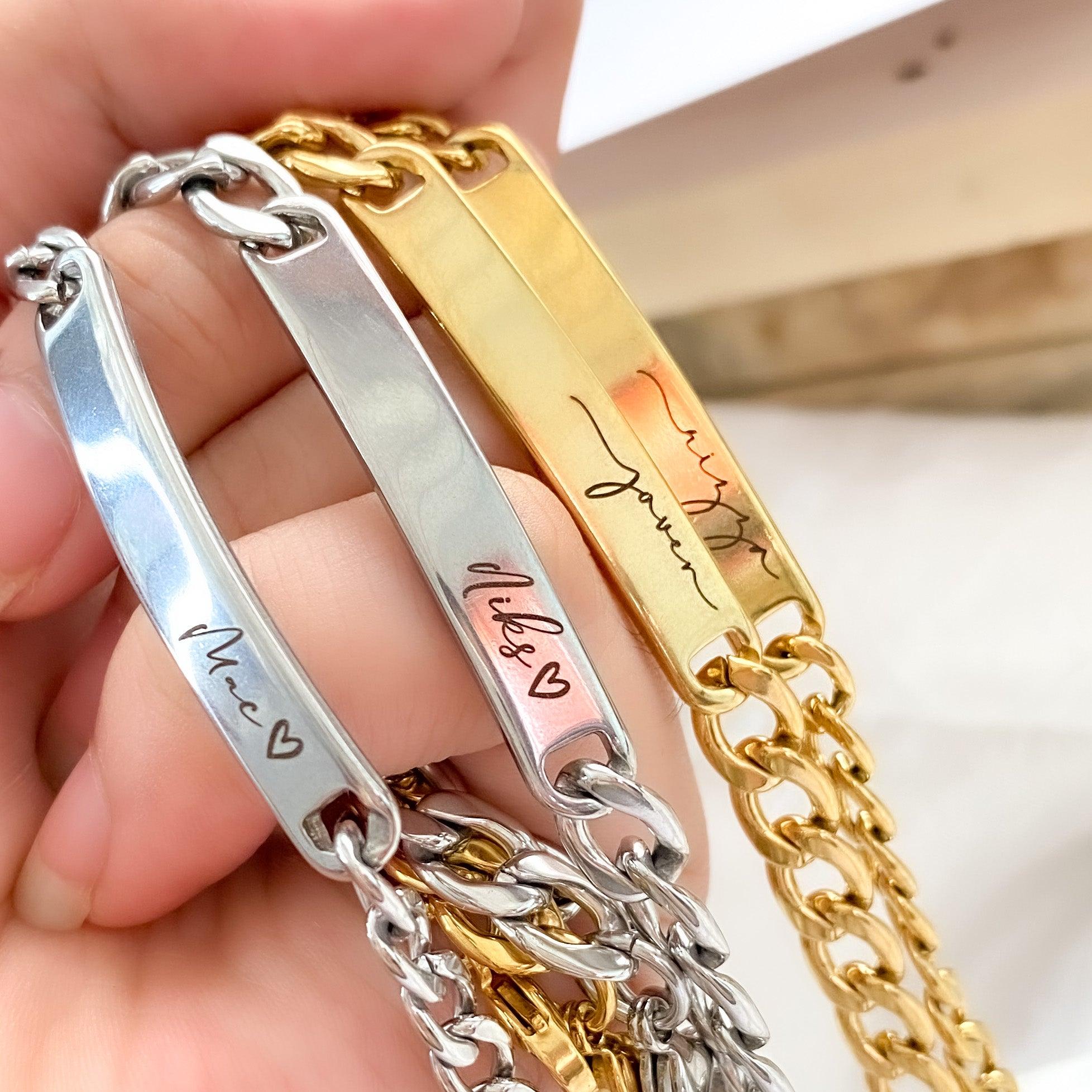 Gold bar bracelet with engraved name on white fabric background